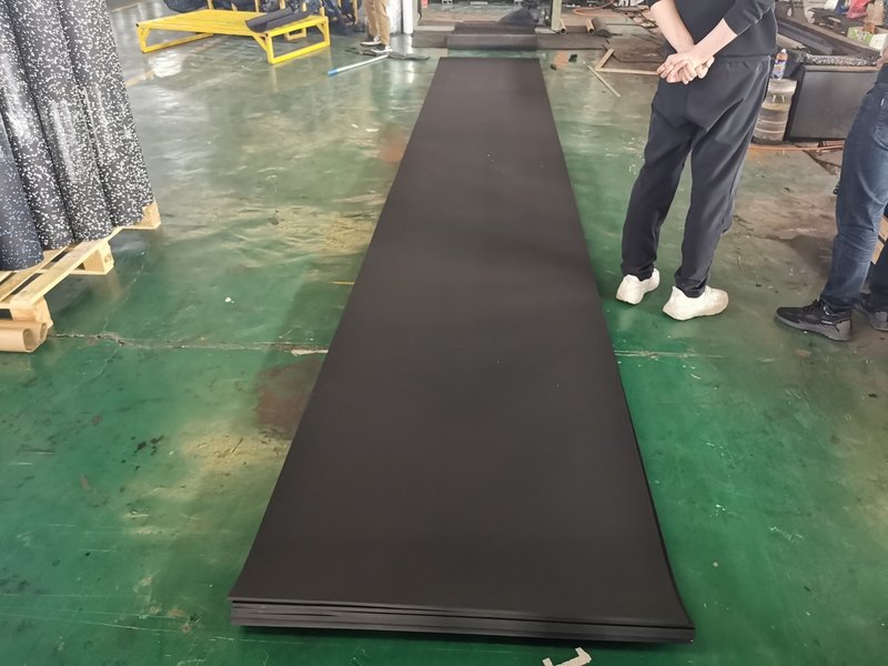 Een smetteloze, moderne sportzaal met naadloze zwarte gerolde rubberen vloeren bezaaid met gekleurde EPDM-vlekken.